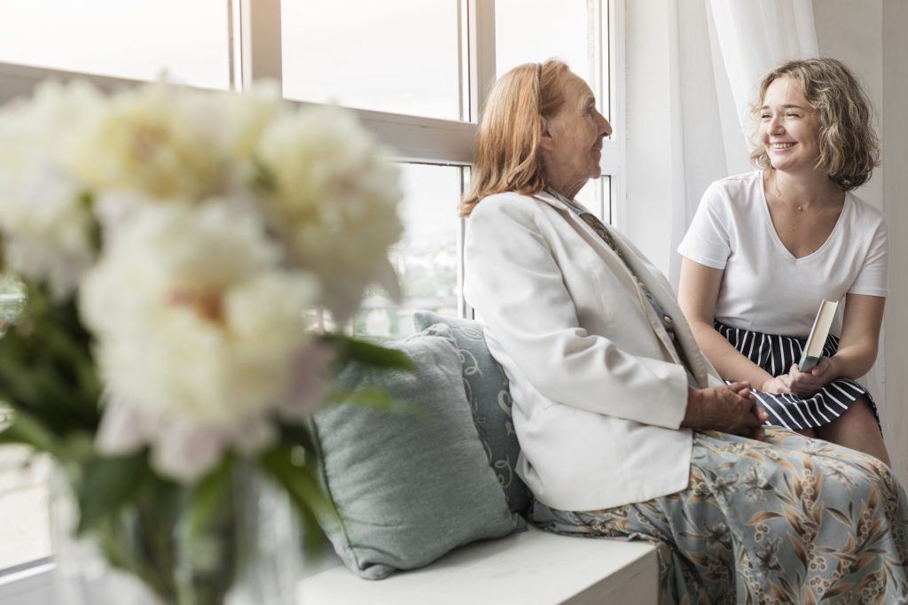ok-smiling-woman-holding-book-sitting-with-her-granny-window-sill